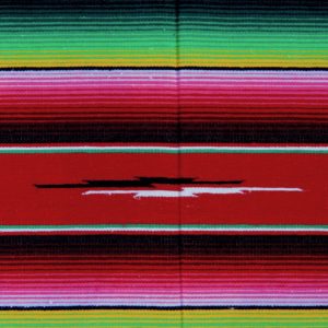 Red Mexican blanket with colourful pink, red, green, yellow and white stripes and a tribal symbol in the middle